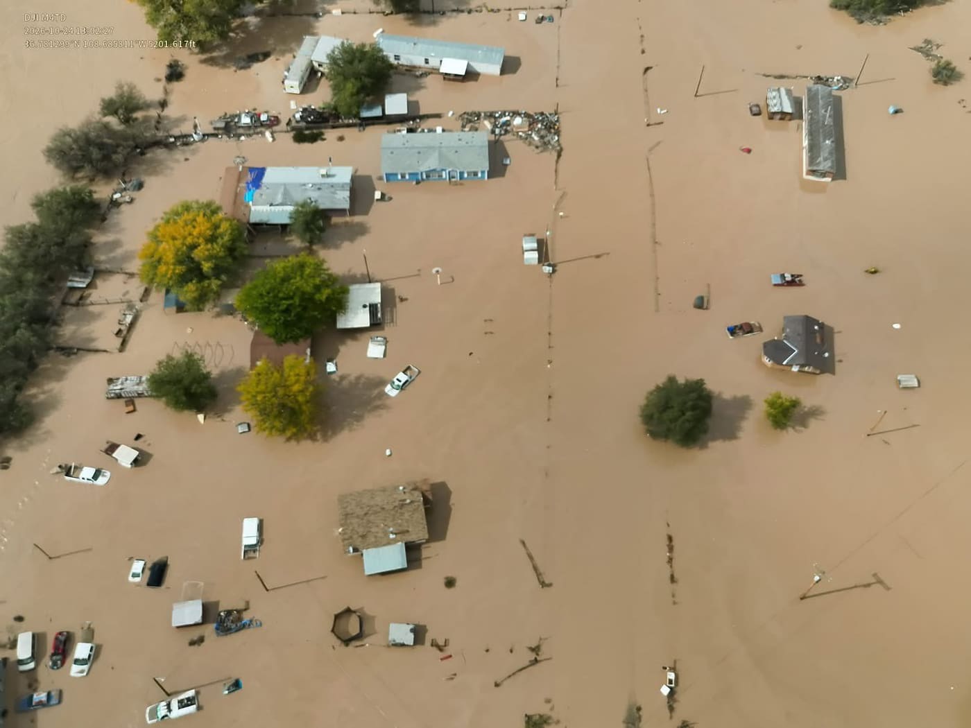Aerial view of homes and roads surrounded by brown floodwater in Shiprock, New Mexico